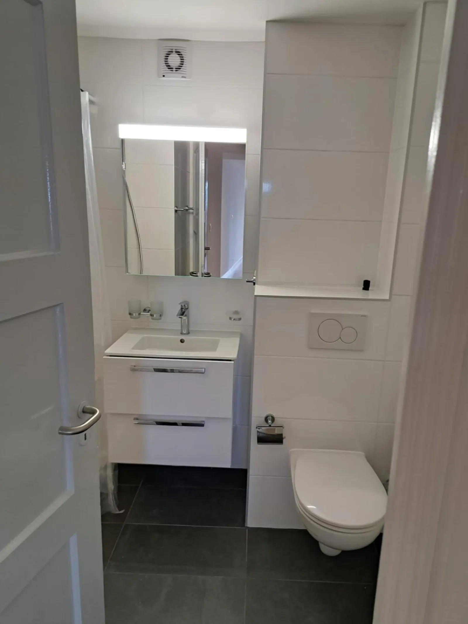 Salle de bain blanche avec WC suspendu et lavabo après rénovation