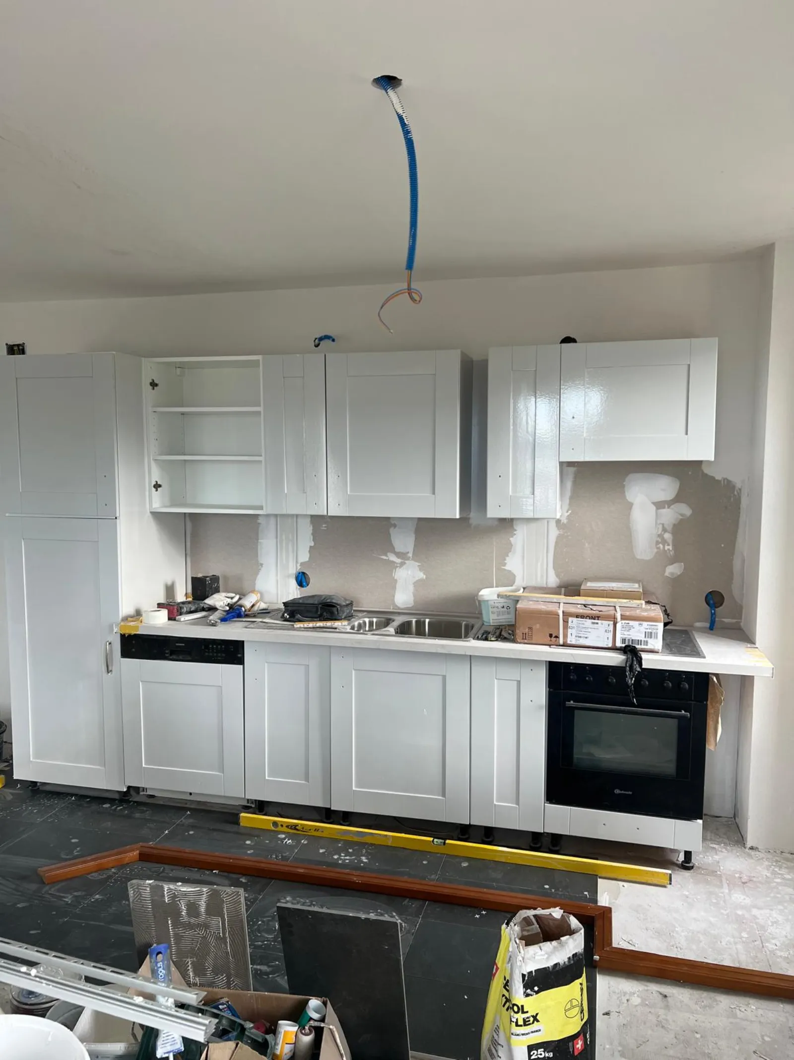 Cuisine pendant la pose des meubles, gaine bleue tirée du plafond