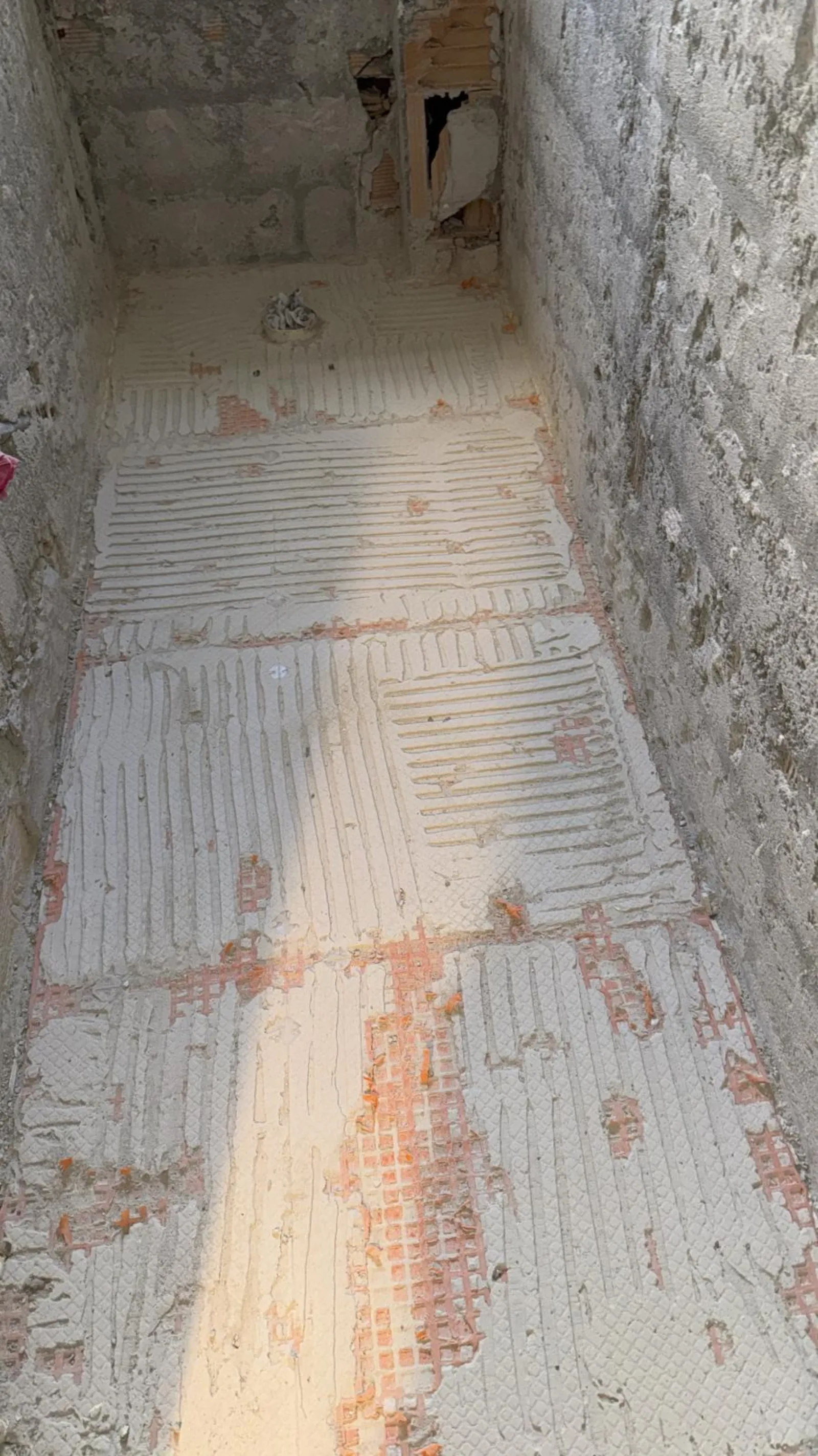 Sol en cours d'encollage avant pose du carrelage en zone douche